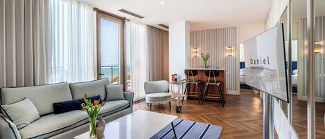 A modern hotel room with a sofa, coffee table, and a view of the ocean.