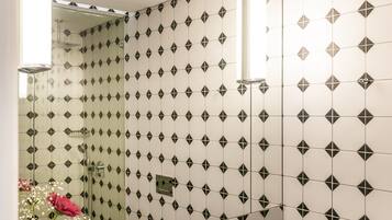 Un baño moderno con pared de azulejos blancos y negros, un espejo grande, encimera negra y lavamanos blanco.