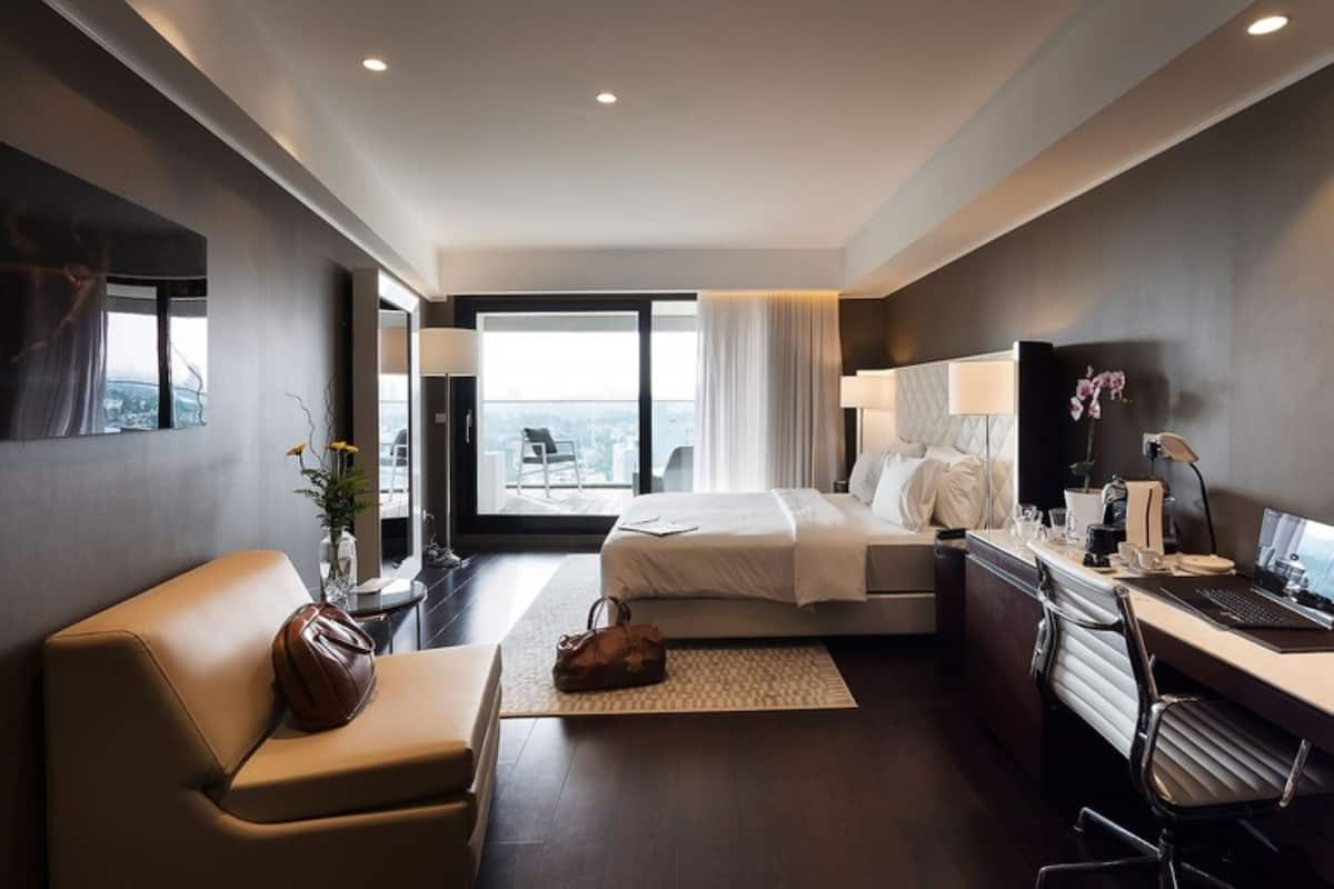 Una habitación de hotel moderna con cama, escritorio, silla y vistas a la ciudad.