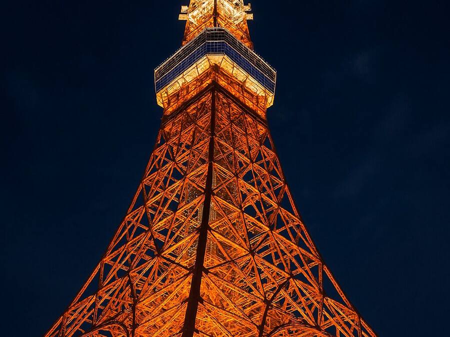 A tall, illuminated tower with a complex iron framework and a pointed top.