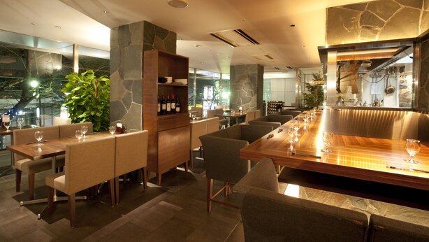 A modern restaurant with a long wooden bar, cushioned seating, and a stone accent wall. - Yaesu Terminal Hotel (Tokyo)