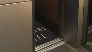 An elevator with a metallic interior and a wooden door. The elevator has a sign that reads "FRONT DESK" and "CACHE CACHE". - Yaesu Terminal Hotel (Tokyo)