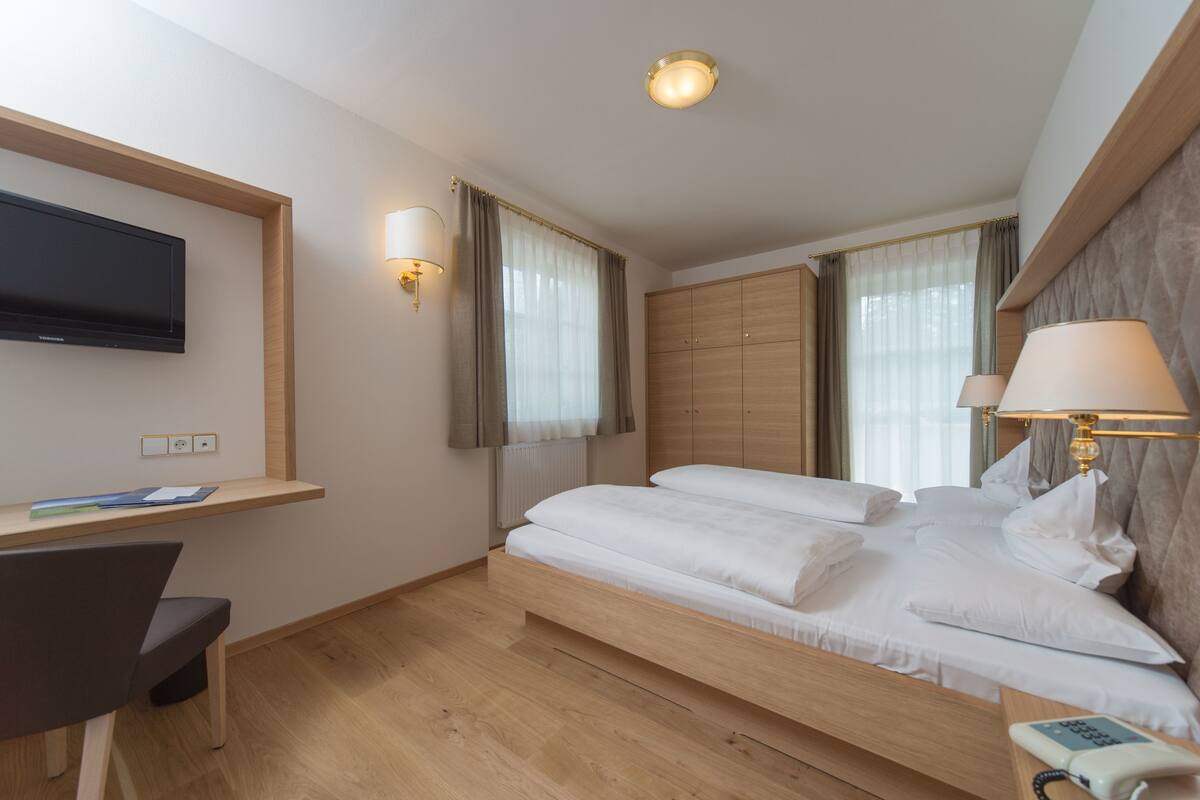 Een hotelkamer met een bed, bureau, televisie en lamp.