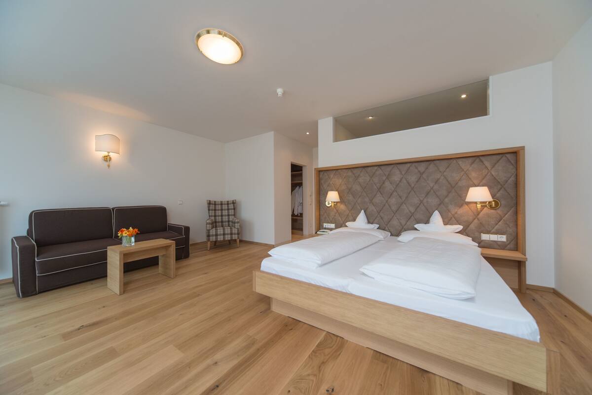 Een moderne hotelkamer met een groot bed, een bank, een klein tafeltje en een stoel.