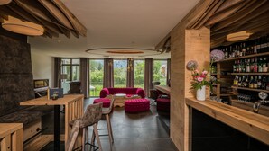 Een modern interieur met houten balken, een bar met flessen en een rode bank.