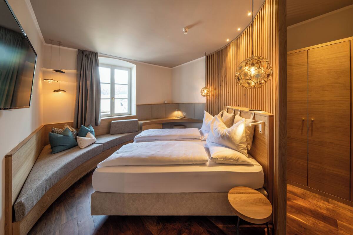 Een moderne hotelkamer met twee bedden, een zithoek, een ruime kledingkast en een aan de muur bevestigde televisie.