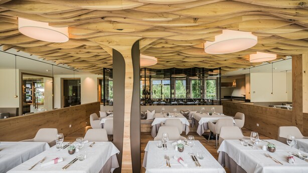 Een restaurant met een houten plafond en witte tafels.
