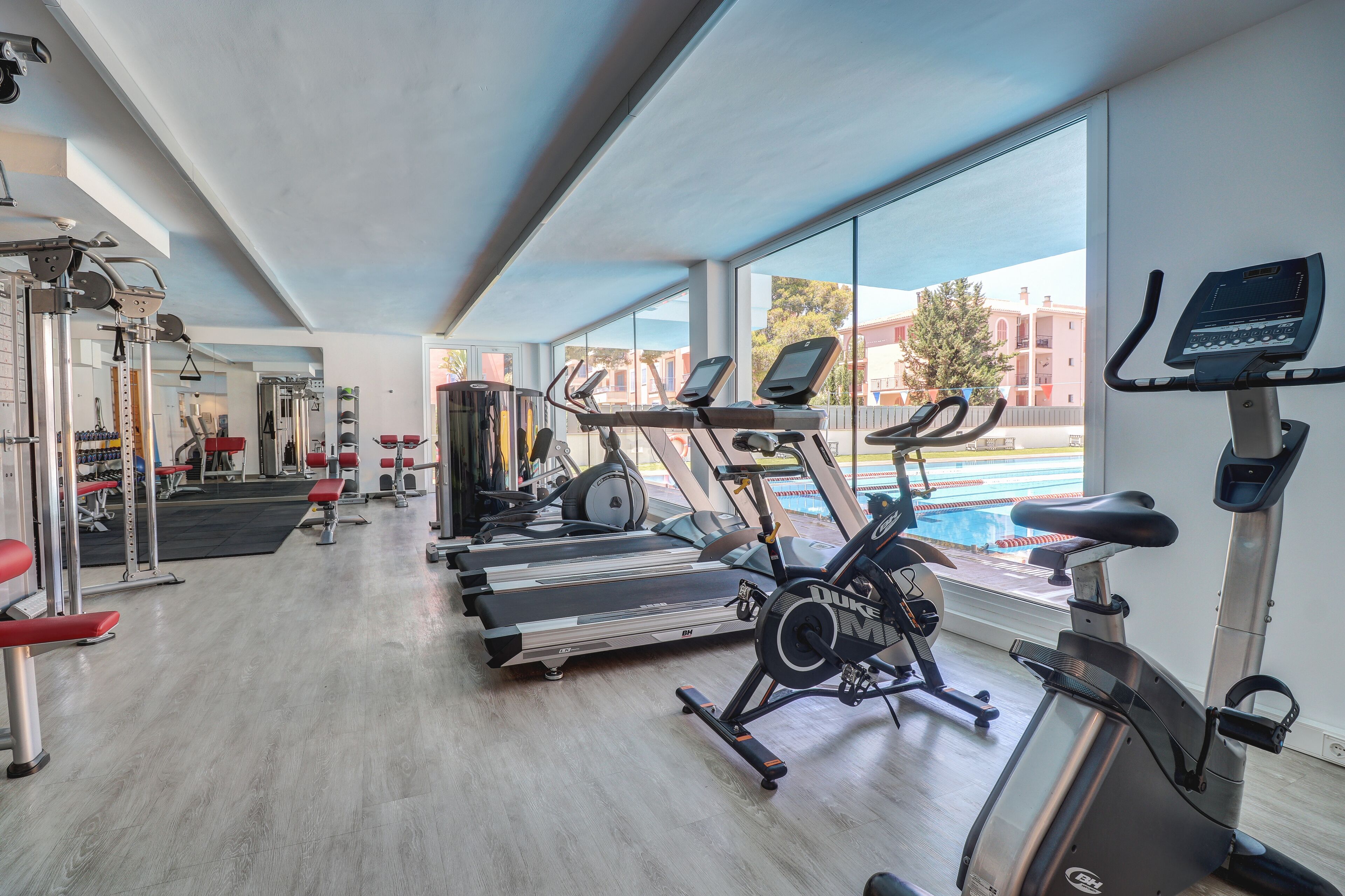 Un gimnasio con cintas de correr, máquinas elípticas y equipo de levantamiento de pesas.