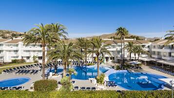 Et resort med flere swimmingpools, palmer og liggestole.