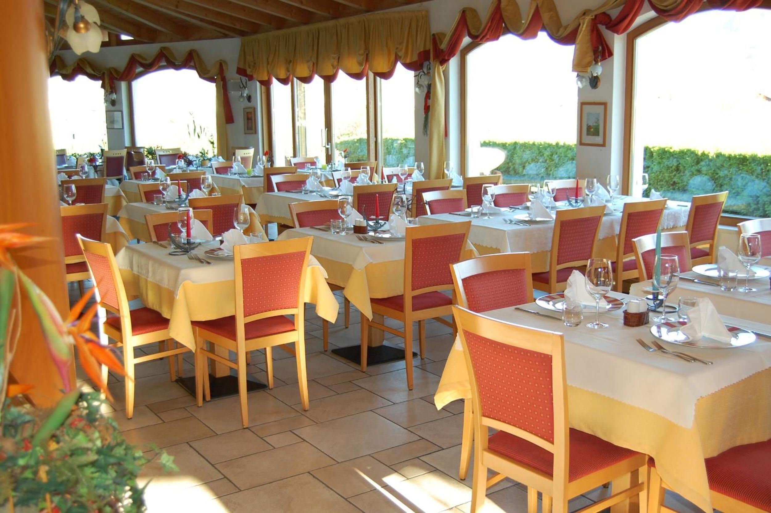 A restaurant with multiple tables and chairs, arranged in a spacious indoor dining area with large windows.
