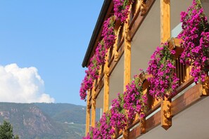 A building with wooden balconies adorned with vibrant flowers. - Gardenhotel Premstaller (Bolzano)