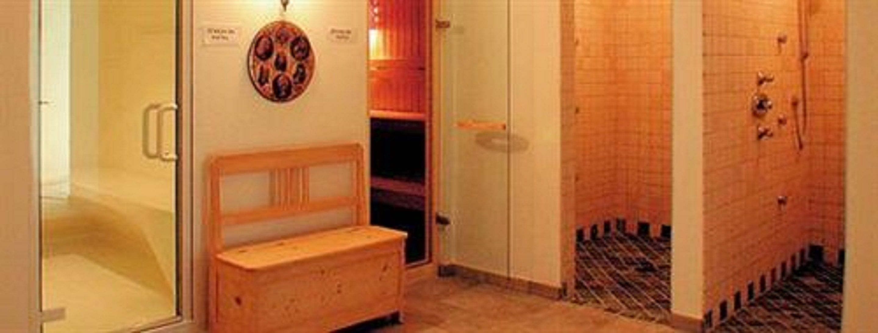 Un sauna avec un banc en bois, un radiateur fixé au mur et un sol carrelé.