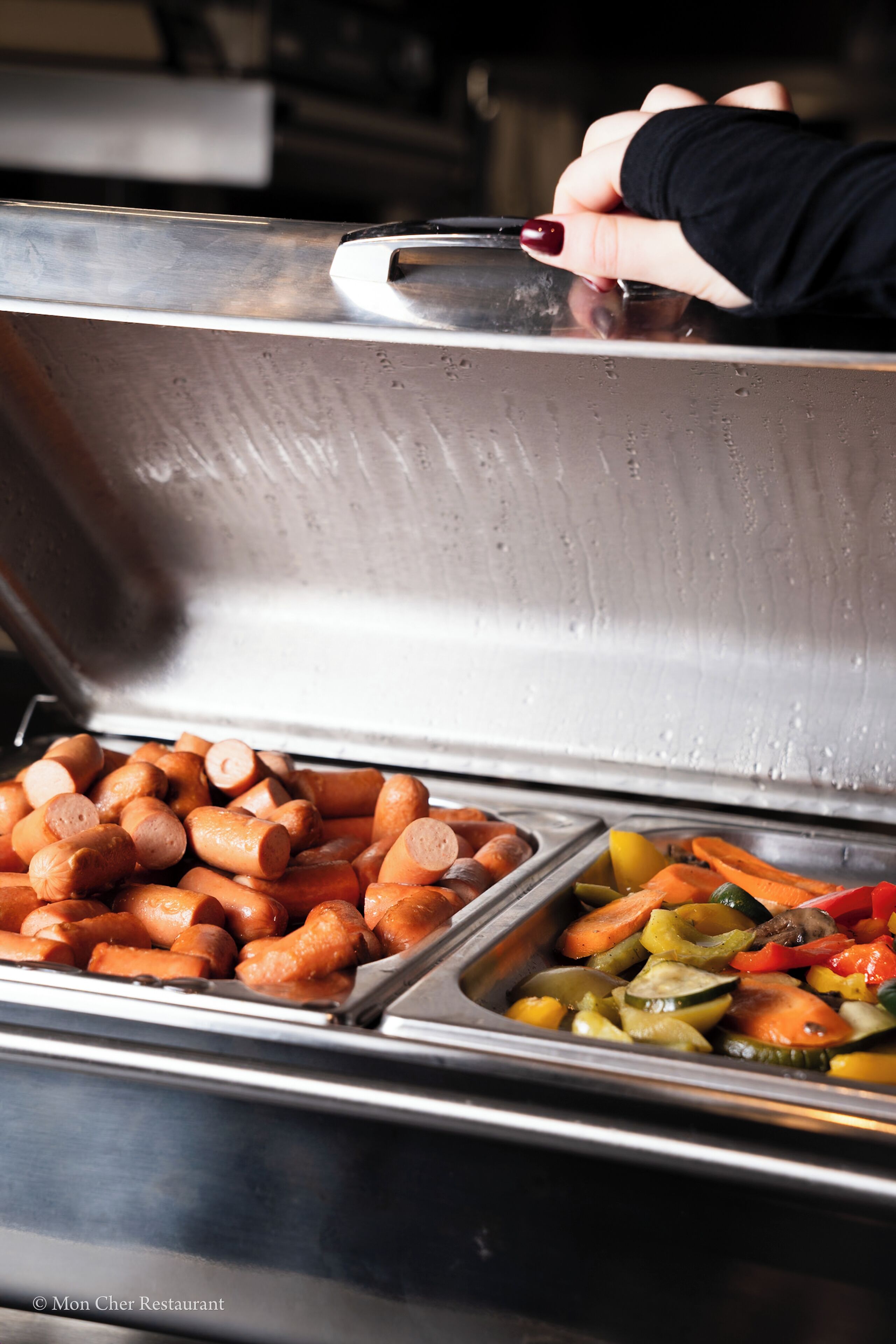 A buffet with various food items including sausages and vegetables.