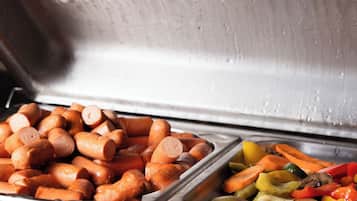 A buffet with various food items including sausages and vegetables.