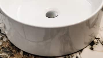 Un lavabo de cerámica blanca con una sola pila, sobre una encimera de mármol.