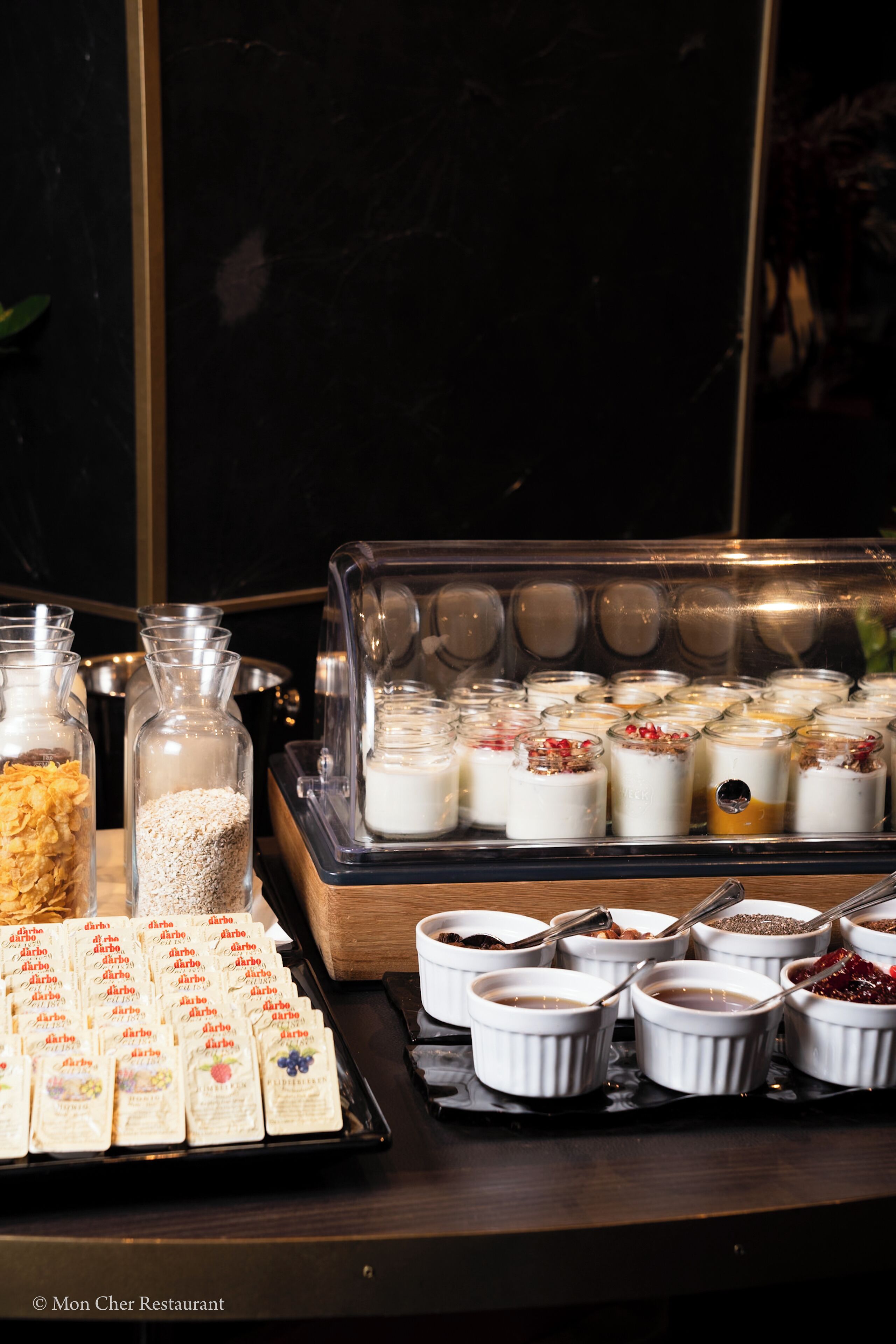 A buffet with various food items, including cereals, yogurt, and desserts.