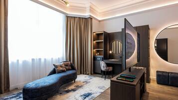 A modern living room with a curved sofa, a flat-screen TV, and a large mirror.