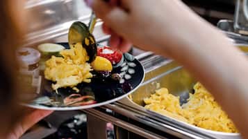 Iemand bedient zichzelf van eten bij een buffet.