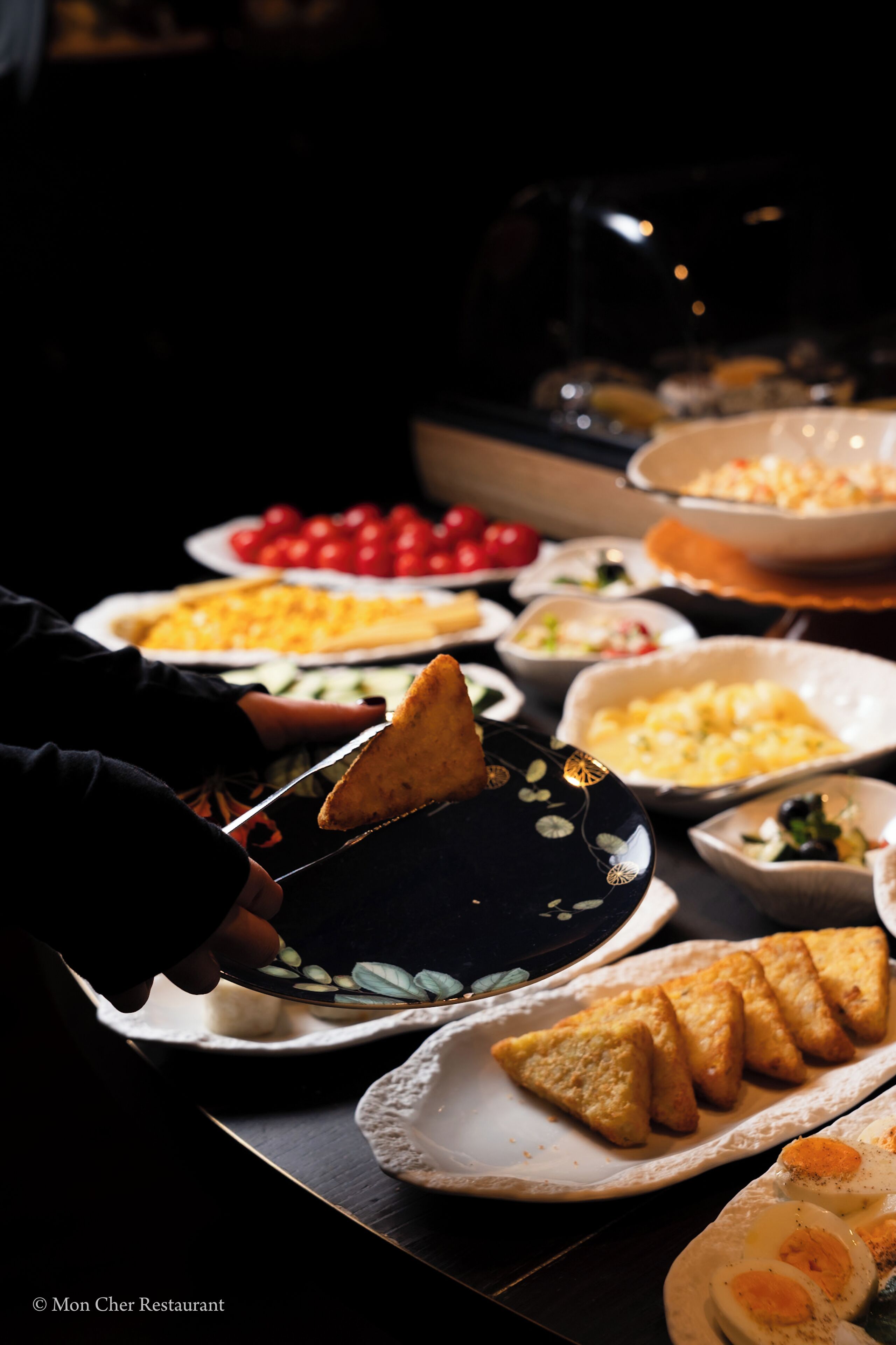 En buffet med forskellige retter, blandt andet et fad med skiveskåret brød, en skål med tomater og en skål med æg.