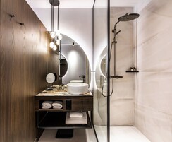 Een moderne badkamer met een houten wastafel, een ronde spiegel, een ruime wasbak en een inloopdouche.