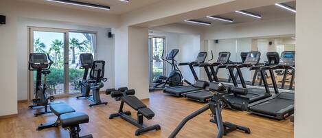 A gym with treadmills, elliptical machines, and benches.