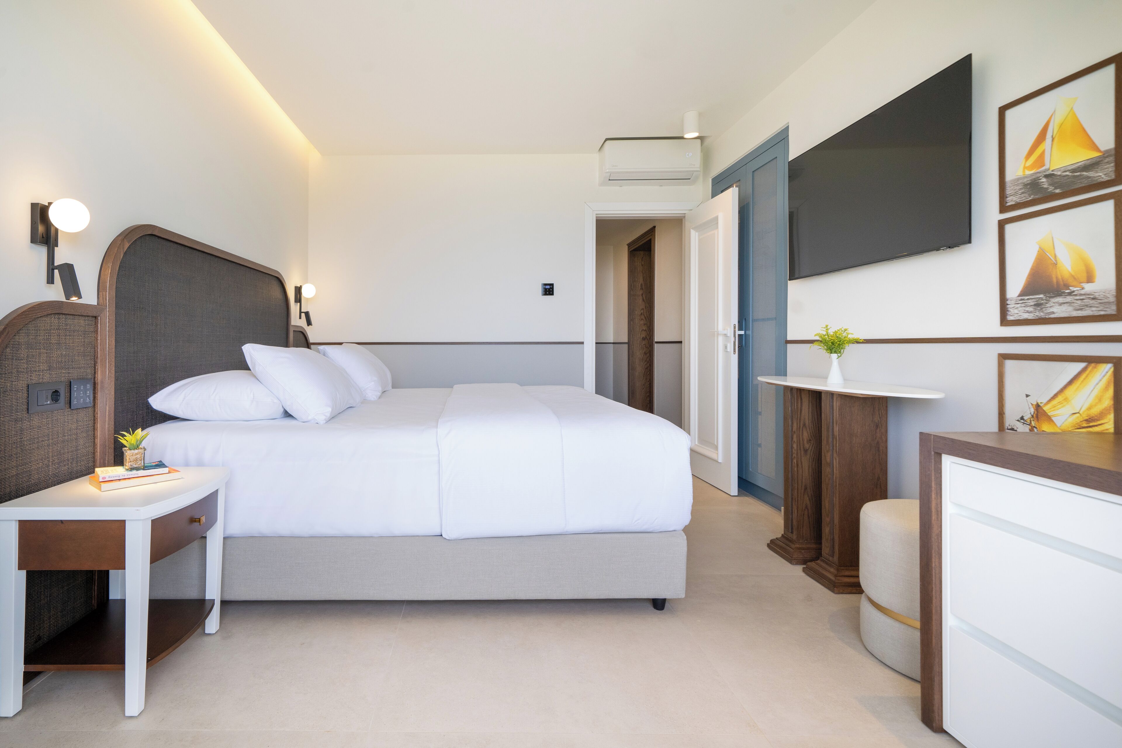 A modern hotel room with a large bed, bedside table, and a TV mounted on the wall.