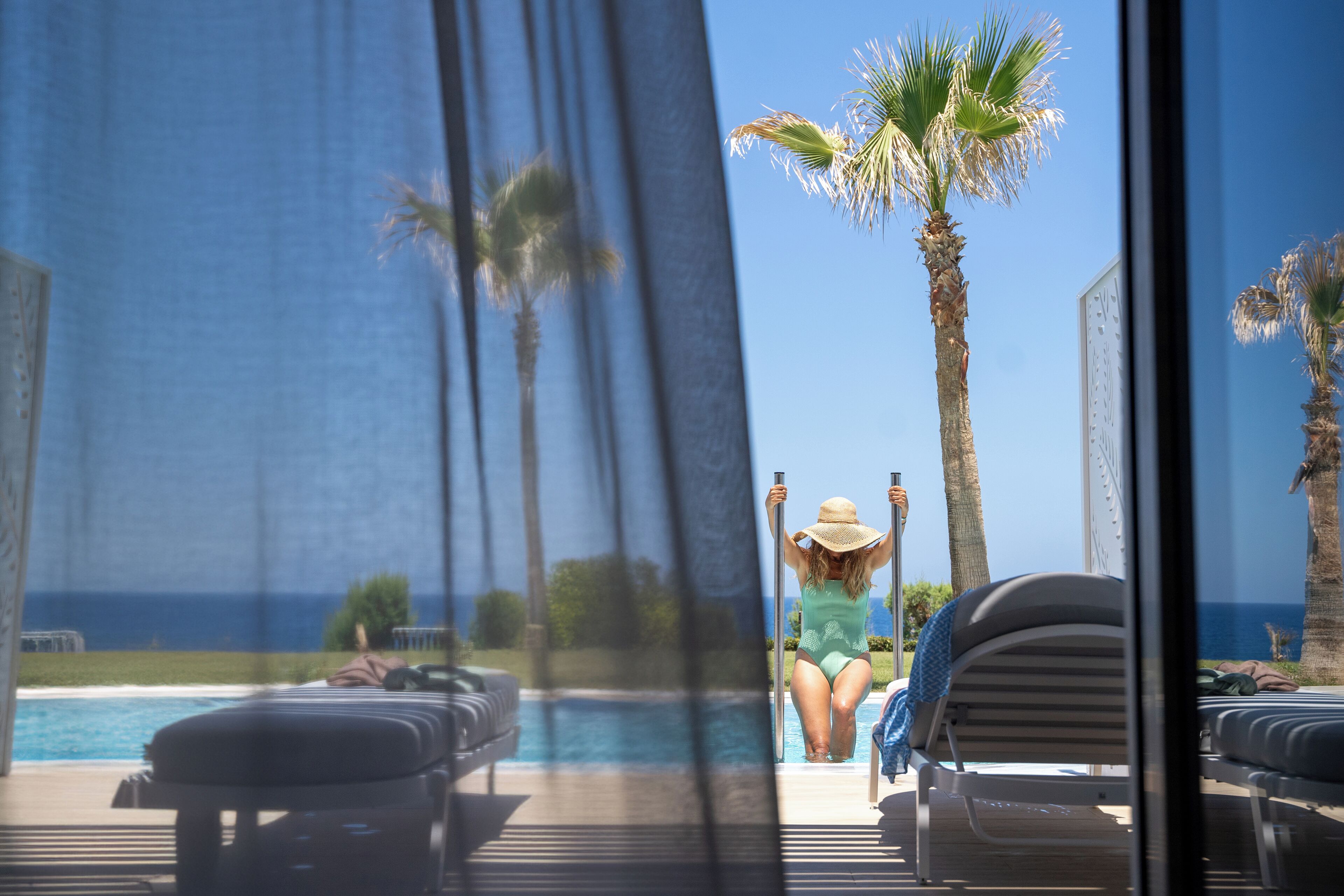 Un espace aménagé au bord de la piscine, avec des chaises longues et une vue sur l’océan.