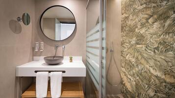 A modern bathroom with a round mirror, a bowl sink, and a glass shower enclosure.