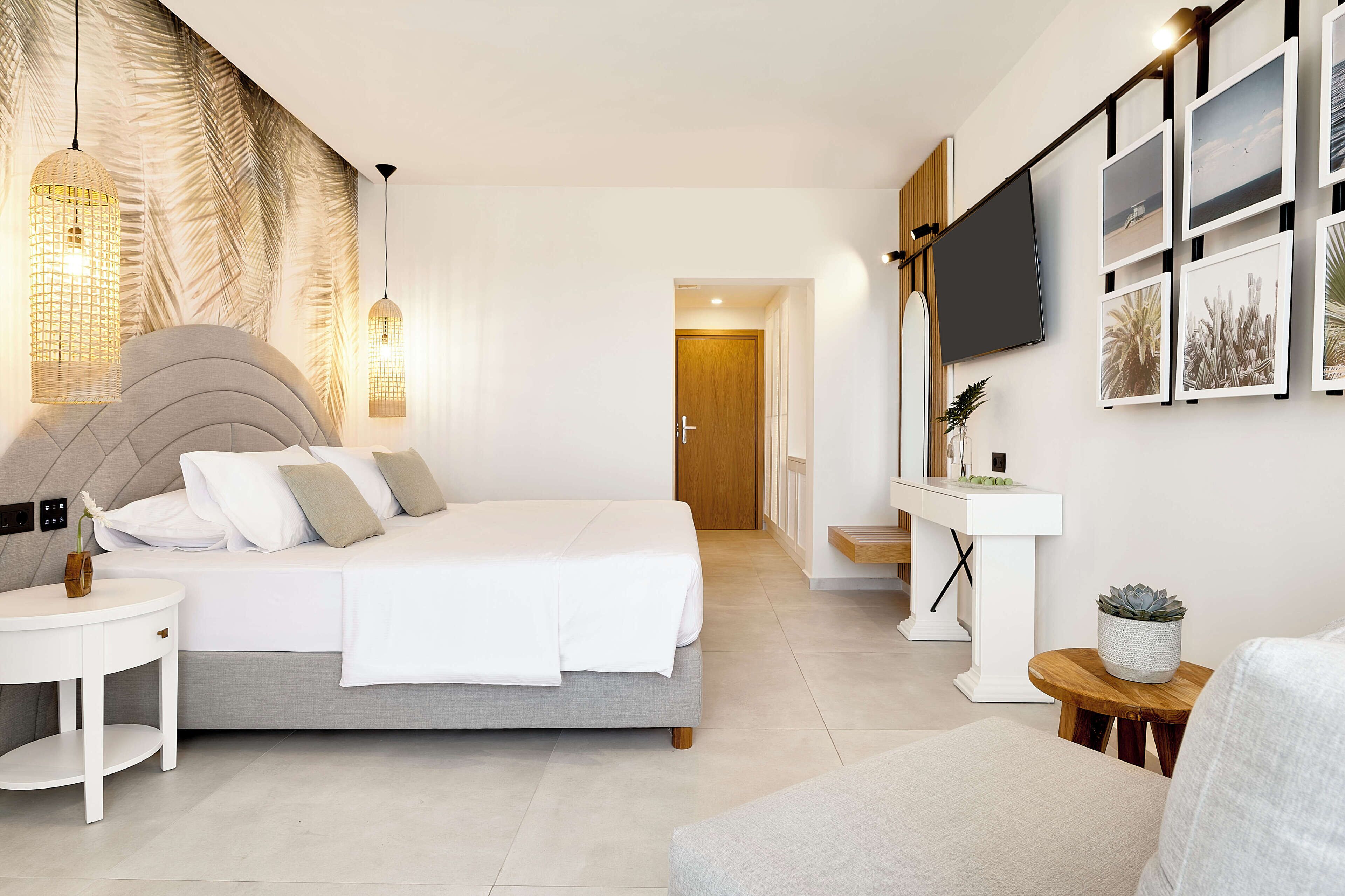 Un dormitorio moderno con una cama grande, mesitas de noche, televisor y una obra de arte colgada en la pared.