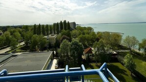 Vista desde un balcón sobre un cuerpo de agua, con edificios y árboles al frente.