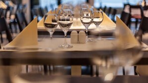 Una mesa de comedor dispuesta con copas de vino y saleros y pimenteros.