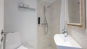 Ein Badezimmer mit Dusche, Toilette, Waschbecken und einem Spiegel mit dekorativem Rahmen.