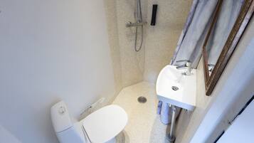 Un baño pequeño y funcional con inodoro, lavamanos y ducha.