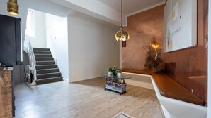 Un intérieur moderne avec un escalier, une table ronde en verre agrémentée de plantes et un banc en bois.