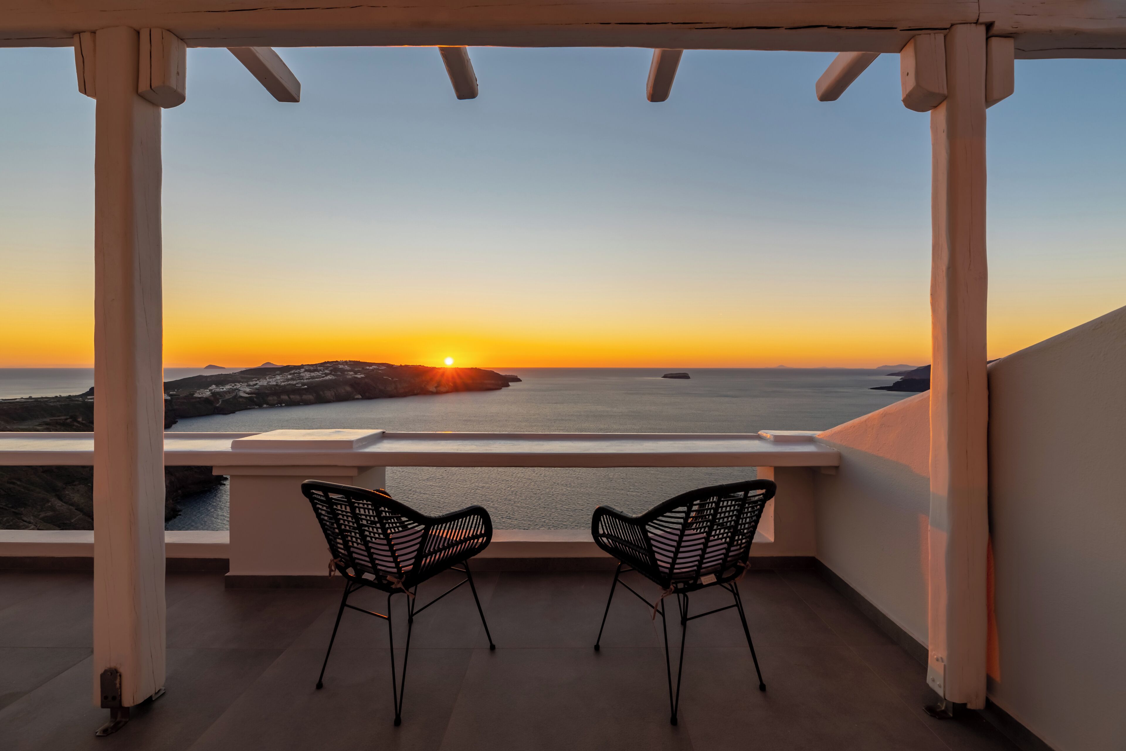 Un balcón con dos sillas que da a una vista del atardecer.