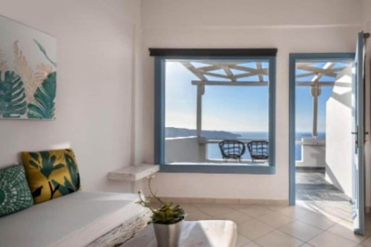 A room with a bed, a window with a view, a small table, and a chair.