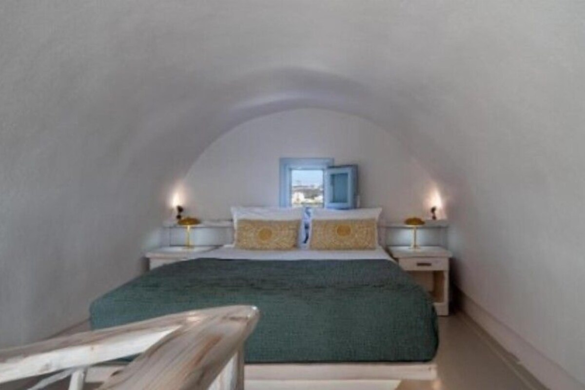 Ein Schlafzimmer mit einem Einzelbett, Nachttischen, einem Fenster und Blick ins Freie.