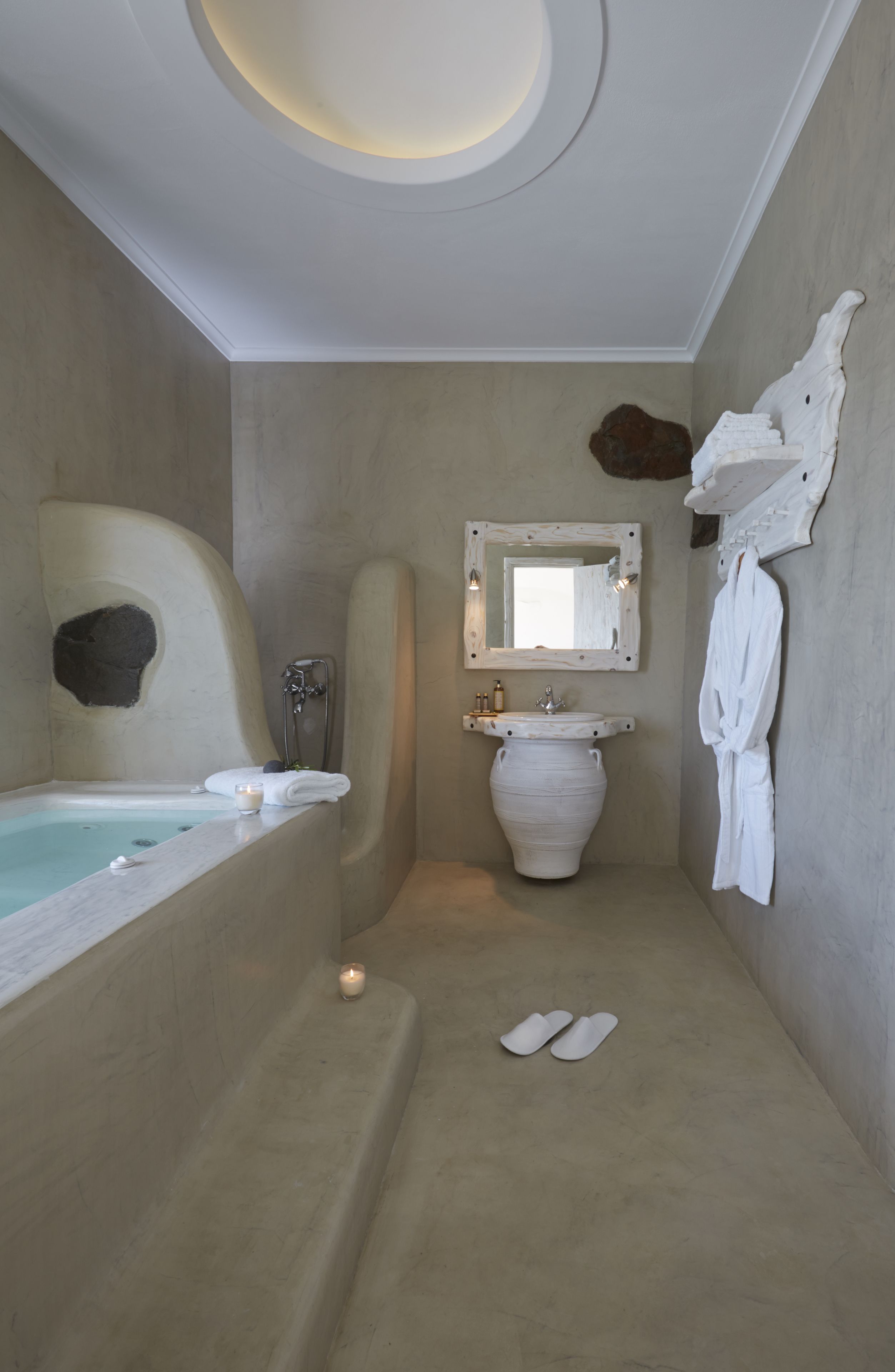 A bathroom with a bathtub, a sink, a mirror, and a robe hanging on the wall.