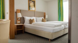 Een hotelkamer met een groot bed, een nachtkastje, een lamp en een schilderij aan de muur.
