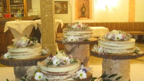Een bruidstaartpresentatie met etagèrs gevuld met taarten, omringd door bloemdecoraties.