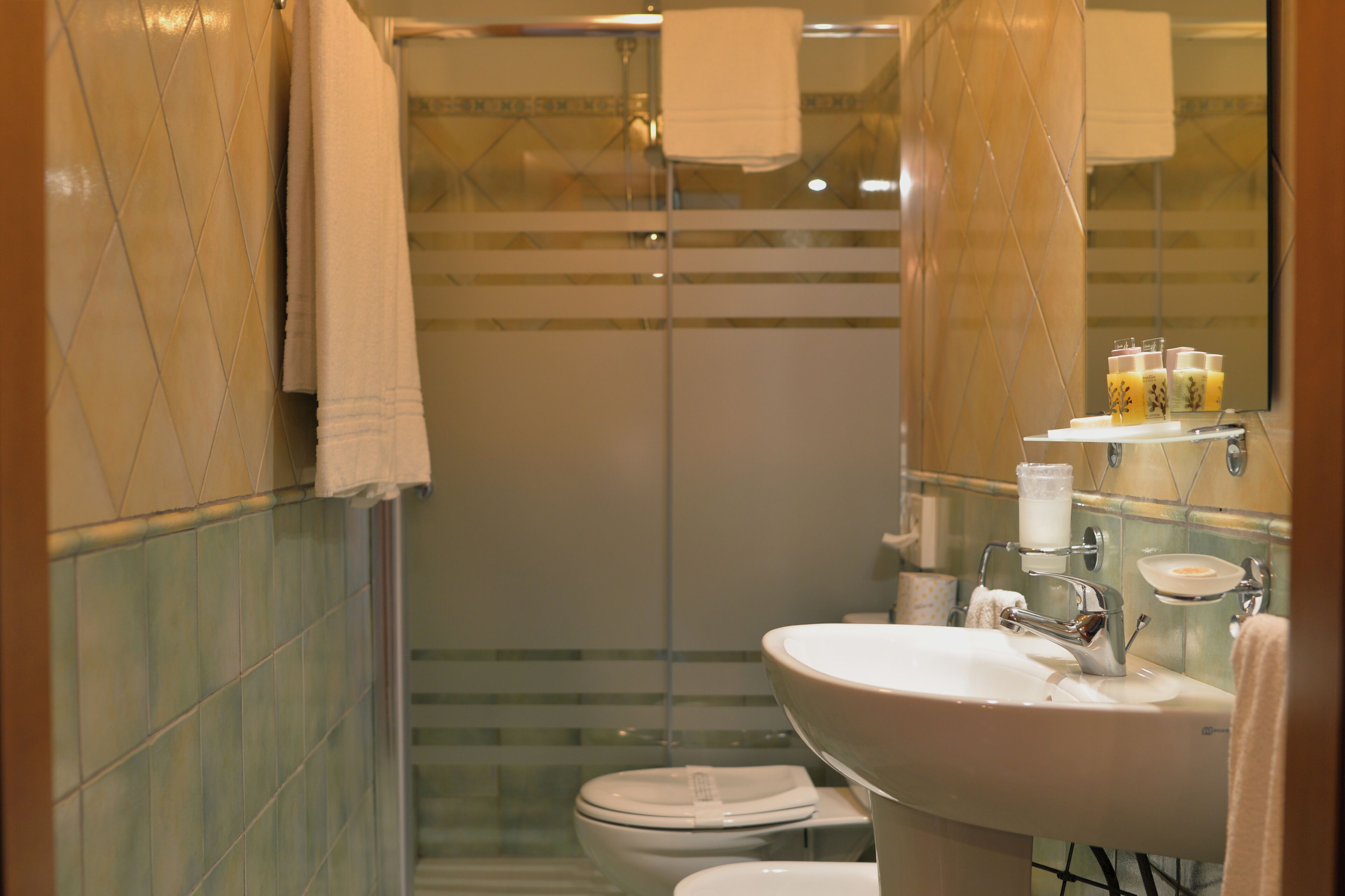 Ein Badezimmer mit Duschkabine aus Glas, Toilette und Waschbecken mit Spiegel.