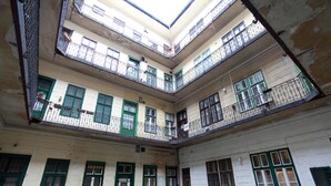 A multi-level courtyard with balconies, green shutters, and a central open space.