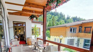 Eine Terrasse im Freien mit Steinböden, Korbmöbeln und hängenden Blumenkörben.
