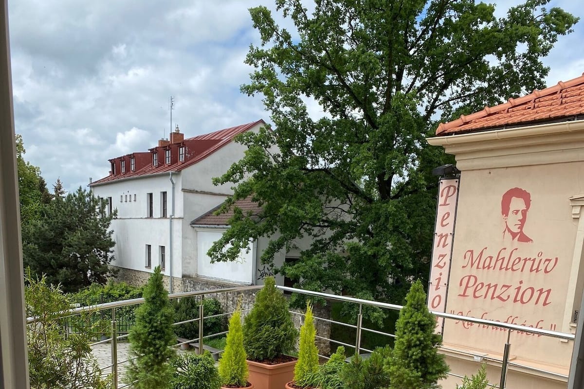 Una terrazza con piante in vaso, mobili da esterno e un edificio con un cartello sullo sfondo.