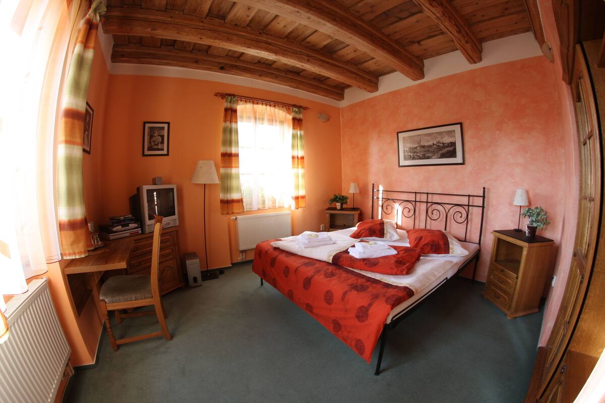 Una camera da letto con un letto, una scrivania, una sedia, un termosifone e una finestra con tende.