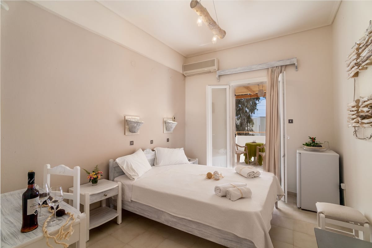 Un dormitorio con cama, mesita de noche y una pequeña mesa con una botella y vasos.