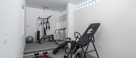 A gym with exercise equipment, a red weight bench, and a large exercise ball.