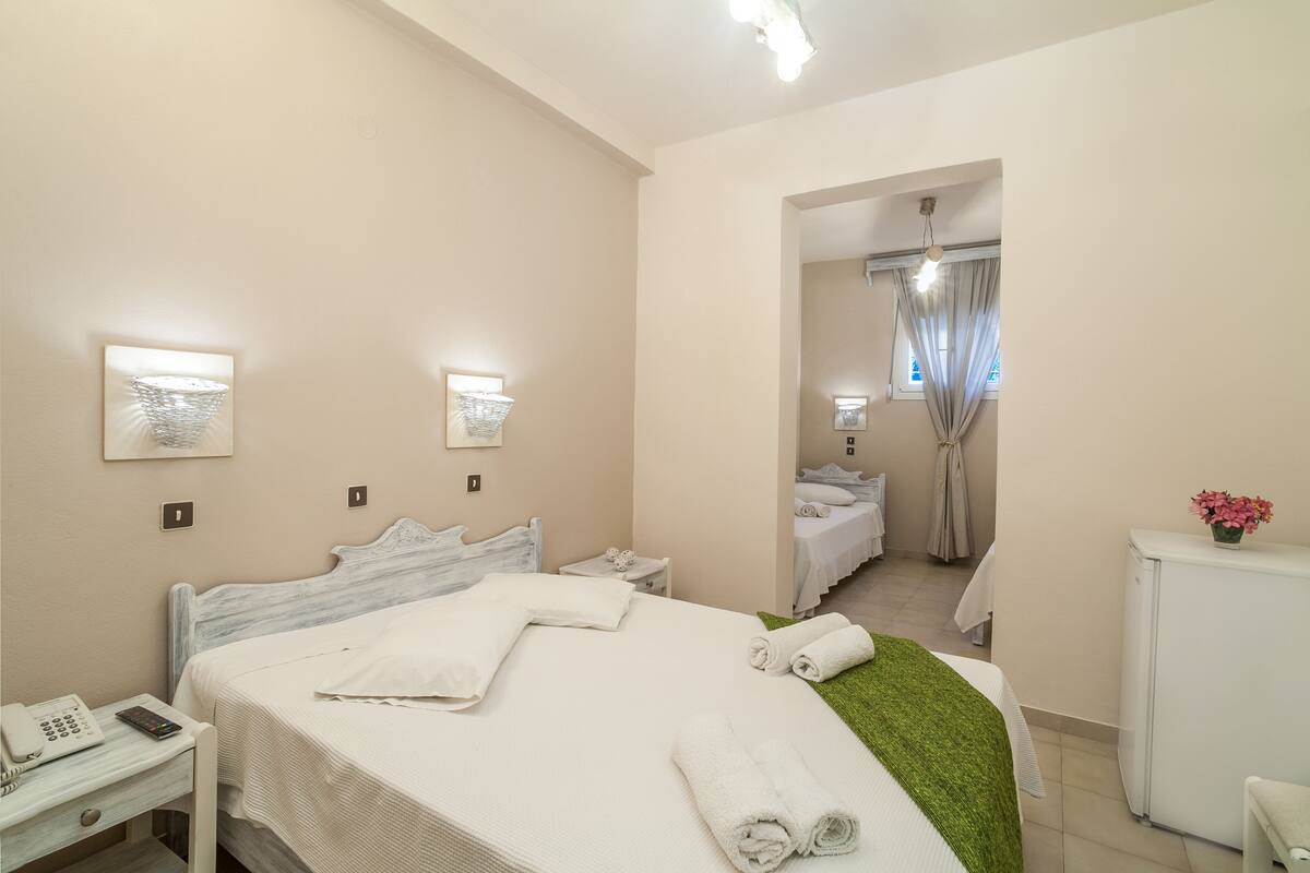 Una habitación de hotel con cama, mesita de noche, lámpara y escritorio con teléfono.