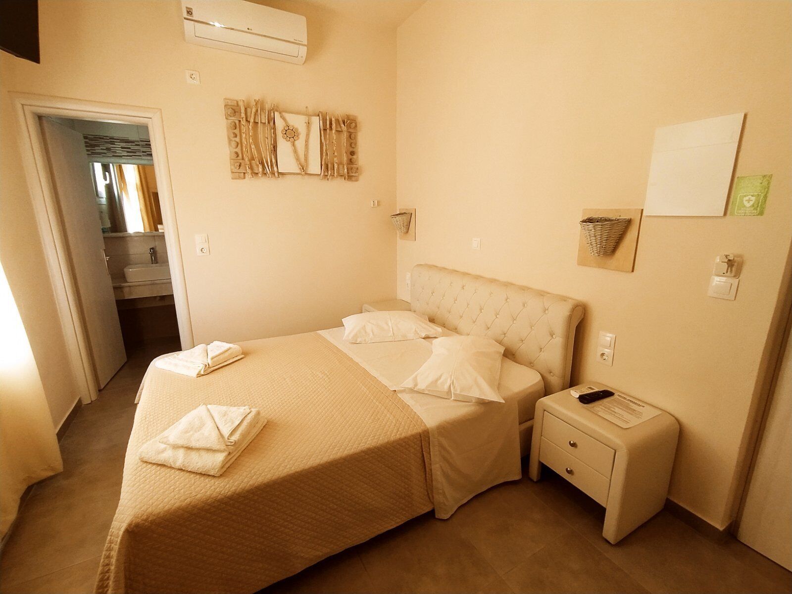 Un dormitorio ordenado con cama, mesitas de noche y una pequeña mesilla.