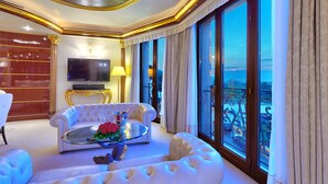 A luxurious living room with a white sofa, a glass coffee table with a floral arrangement, and a large TV. - Mulino Luxury Boutique Hotel (Buje)